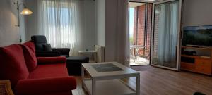 a living room with a red couch and a tv at Exklusive Ferienwohnung am Südstrand mit Wintergarten & Hafenblick Wohnung 113 in Wilhelmshaven