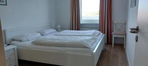 a white bed in a bedroom with a window at Exklusive Ferienwohnung am Südstrand mit Wintergarten & Hafenblick Wohnung 113 in Wilhelmshaven