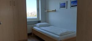 a small bed in a room with a window at Exklusive Ferienwohnung am Südstrand mit Wintergarten & Hafenblick Wohnung 113 in Wilhelmshaven
