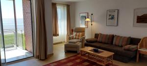 a living room with a couch and a chair at Exklusive Ferienwohnung am Südstrand mit Wintergarten, Balkon & Meerblick Wohnung 22 in Wilhelmshaven
