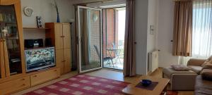 a living room with a couch and a tv and a table at Exklusive Ferienwohnung am Südstrand mit Wintergarten, Balkon & Meerblick Wohnung 22 in Wilhelmshaven