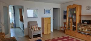 a living room with a chair and a cabinet at Exklusive Ferienwohnung am Südstrand mit Wintergarten, Balkon & Meerblick Wohnung 22 in Wilhelmshaven