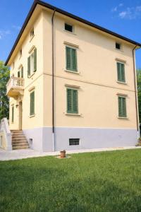a large building with green windows and a grass field at Appartamento Santa Maria Nuova in Reggio Emilia