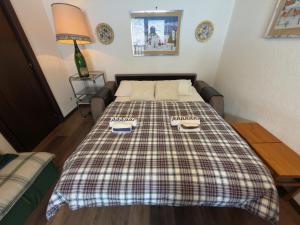 a bed in a room with a plaid blanket on it at Neve 5 Apartment - Clotes Slope Access in Sauze d'Oulx +11 photos