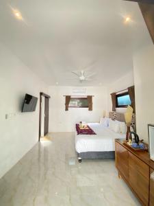 een slaapkamer met een wit bed en een tv bij Villa Collard in Senggigi 