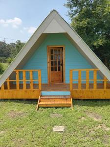 a small blue house with a porch and a door at Dam Jam Cabanas in Oranjeville