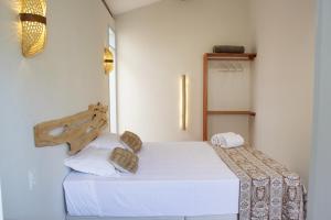a bedroom with a white bed with a wooden headboard at Vila Refúgio in Aracati +77 photos