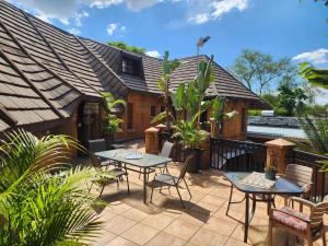 a patio with tables and chairs and a house at Green Haven Guest Lodge in Pretoria