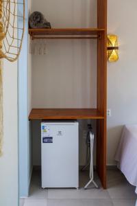 a shelf over a small refrigerator in a room at Vila Refúgio in Aracati