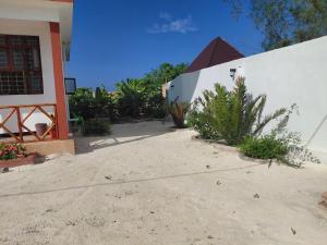 a house with a white wall and some plants at Karibu House Bwejuu in Bwejuu