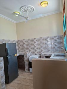 a kitchen with a black refrigerator and tile walls at Karibu House Bwejuu in Bwejuu