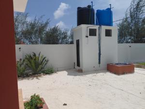 a white building with a gate and a fence at Karibu House Bwejuu in Bwejuu