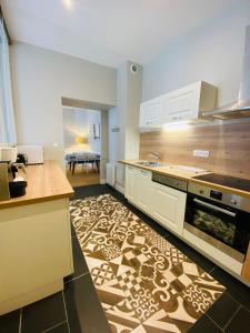 een keuken met witte kasten en een gedessineerde vloer bij Le Gîte Du Parc avec parking vieux port et plage au calme in La Rochelle