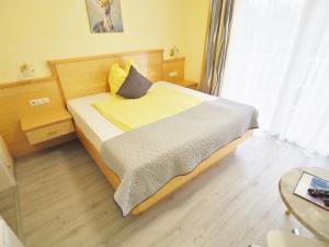 ein Schlafzimmer mit einem Bett mit gelben Laken und einem Fenster in der Unterkunft Pension Kathi in Sankt Kanzian am Klopeiner See