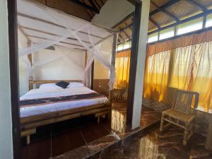 a bedroom with a canopy bed and a chair at Tutwin Guesthouse in Krambitan +1 photo