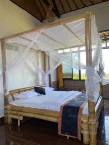 a bedroom with a bed with a canopy at Tutwin Guesthouse in Krambitan