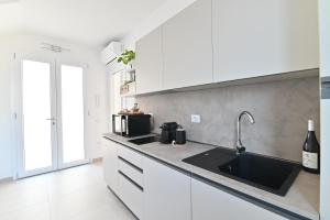 a kitchen with white cabinets and a sink at Congiu's Apartments in Pula
