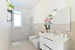 a white bathroom with a sink and a toilet at Congiu's Apartments in Pula +11 photos