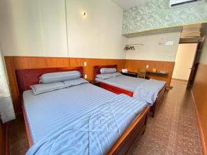 two twin beds in a room with a desk at Văn An Hotel in Ho Chi Minh City +5 photos
