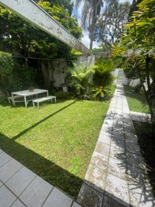 a garden with a table and a bench on the grass at Bergamota Hostel in Curitiba
