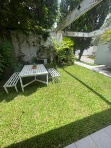 a picnic table and bench in a yard with grass at Bergamota Hostel in Curitiba