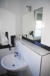a white bathroom with a sink and a mirror at Aparthotel Magnolia in Oberursel +64 photos