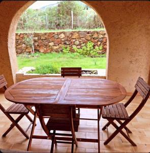 a wooden table and chairs in a patio with a stone wall at Résidence Palmarella in Galeria