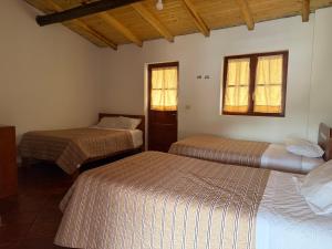 a room with two beds and two windows at Alonso, Fogón & Posada in Chacas +13 photos