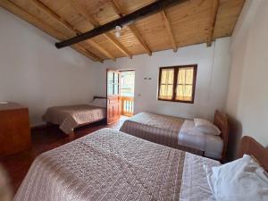 a bedroom with two beds in a room with wooden ceilings at Alonso, Fogón & Posada in Chacas