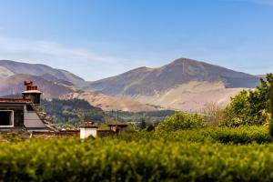 una vecchia casa in un campo con montagne sullo sfondo di Woodside B & B a Keswick