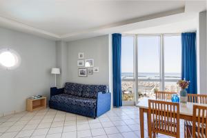 een woonkamer met een blauwe bank en een tafel bij Hotel Valverde & Residenza in Cesenatico