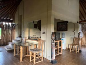 a room with a table and chairs and a kitchen at Cacao Bamboo House in Krambitan