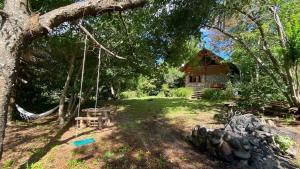 a swing in front of a log cabin at Cabaña Mirador del Valle in Lago Puelo