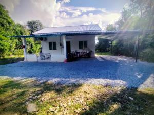 a small white house with a gravel yard at Sri Nawa Homestay in Pokok Sena