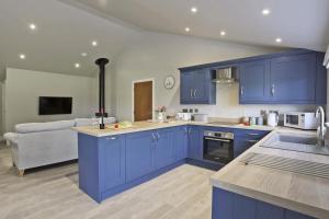 a kitchen with blue cabinets and a living room at 3 Bed in Barsham oc-bbarn in Beccles