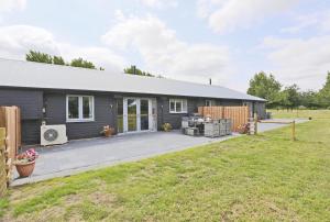 a gray house with a patio and a yard at 3 Bed in Barsham oc-bbarn in Beccles