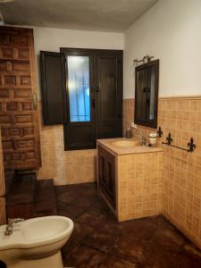 a bathroom with a toilet and a sink and a mirror at Hostal Casa Inés La Valerosa in Las Navas de la Concepción