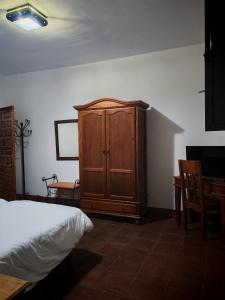 a bedroom with a wooden cabinet and a table at Hostal Casa Inés La Valerosa in Las Navas de la Concepción