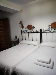 two beds in a room with white sheets and towels at Hostal Casa Inés La Valerosa in Las Navas de la Concepción