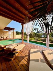 an outdoor deck with lounge chairs and a swimming pool at Luxury Ocean View Villa in Brisas de Zicatela