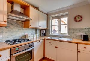 a kitchen with white cabinets and a stove top oven at 2 Bed in Southwold oc-scl in Reydon +4 photos