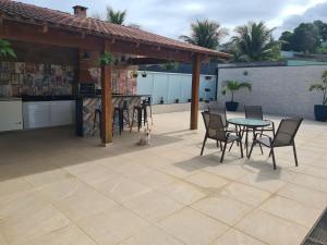 a patio with a table and chairs and a bar at House in Iriri in Anchieta