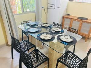 a dining room table with chairs and a glass table and chairsktop at House in Iriri in Anchieta