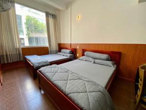 two beds in a room with a window at Văn An Hotel in Ho Chi Minh City