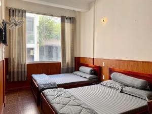 a room with three beds and a window at Văn An Hotel in Ho Chi Minh City