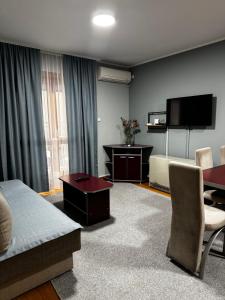 a living room with a couch a table and a tv at IWA CENTAR Apartments & Wellness in Vrnjačka Banja