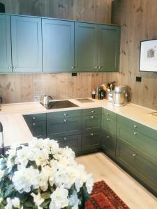 een keuken met groene kasten en een vaas met bloemen bij Mountain Cabin With Panoramic Views In Oppdal in Gorset