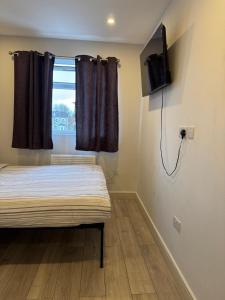 a bedroom with a bed and a tv on the wall at Brigstock 4 in Thornton Heath
