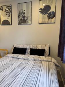a bedroom with a bed with four pictures on the wall at Brigstock 4 in Thornton Heath