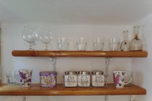 a shelf with glasses and wine glasses on it at Happy Place Apartment in Lupeni
